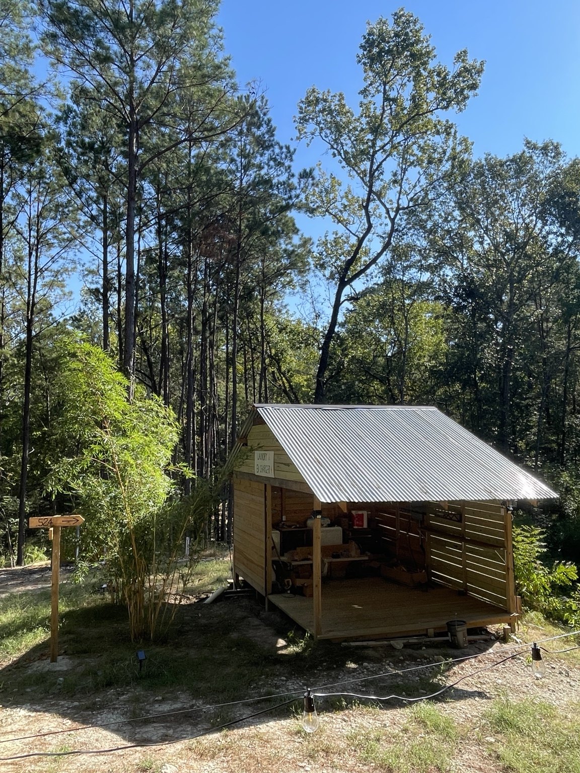 Semi-open wooden laundry pavilion surrounded by forest