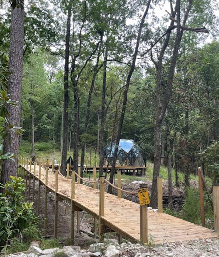 Long elevated wooden bridge leading through trees toward 526 Orbit